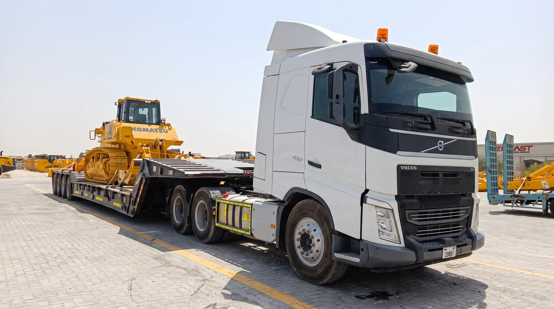 White Volvo lowbed carrying a tracked bulldozer